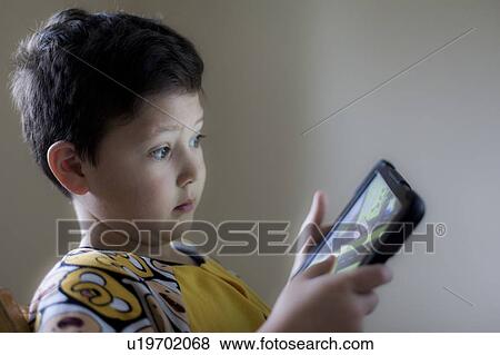 Stock Photo - Young boy playing on handheld device. Fotosearch