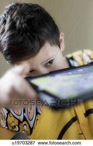 Stock Photo - Young boy playing on handheld device. Fotosearch