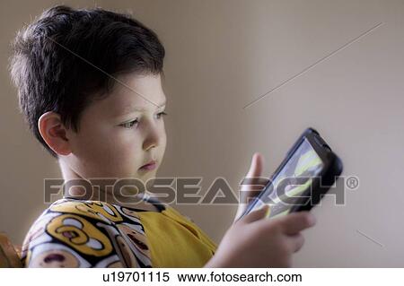 Stock Photography - Young boy playing on handheld device. Fotosearch