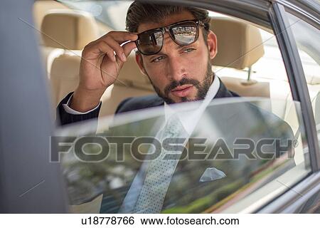 Young businessman holding up sunglasses in car backseat, Dubai, United Arab Emirates View Large Photo Image Stock Photograph - Young businessman holding up sunglasses in car backseat, Dubai, United Arab Emirates. Fotosearch