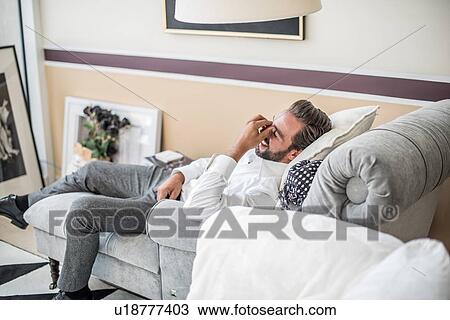 Young businessman reclining and laughing on hotel room chaise longue, Dubai, United Arab Emirates View Large Photo Image Stock Image - Young businessman reclining and laughing on hotel room chaise longue, Dubai, United Arab Emirates. Fotosearch