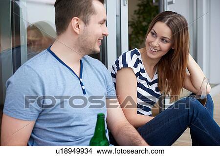 Young couple sitting outdoors, drinking bottled beer View Large Photo Image Picture - Young couple sitting outdoors, drinking bottled beer. Fotosearch