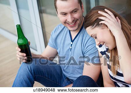 Young couple sitting outdoors, drinking bottled beer View Large Photo Image Stock Photo - Young couple sitting outdoors, drinking bottled beer. Fotosearch