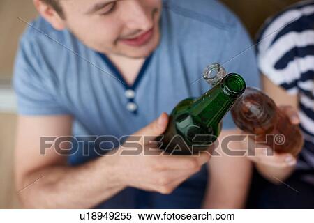 Young couple sitting outdoors, toasting with bottled beers View Large Photo Image Stock Photography - Young couple sitting outdoors, toasting with bottled beers. Fotosearch