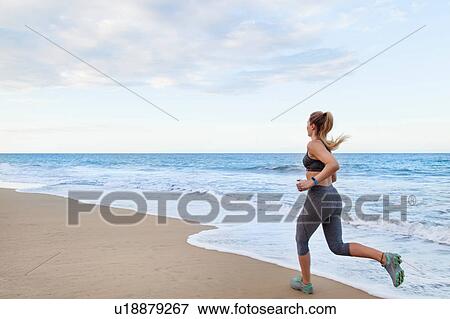 Stock Photo - Young female runner running on beach, Dominican Republic, The Caribbean. Fotosearch