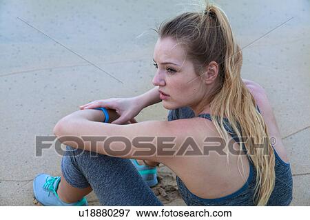 Stock Photo - Young female runner sitting on beach, Dominican Republic, The Caribbean. Fotosearch
