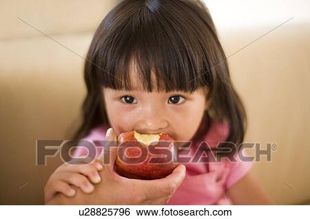 Stock Photograph - Young girl eating an apple. Fotosearch