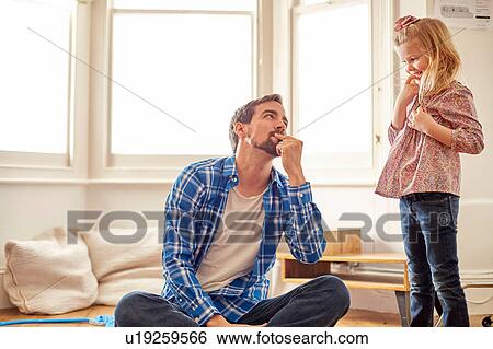 Young girl looking at her father, with mischievous expression View Large Photo Image Stock Photograph - Young girl looking at her father, with mischievous expression. Fotosearch
