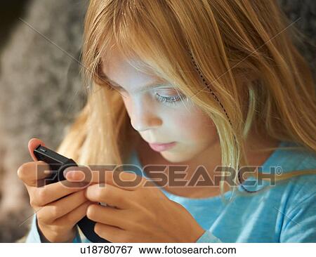 Young girl looking at smartphone, face illuminated by glow of screen View Large Photo Image Stock Photo - Young girl looking at smartphone, face illuminated by glow of screen. Fotosearch