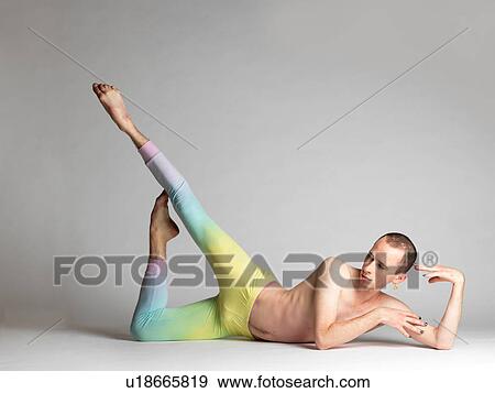 Stock Photo - Young male dancer wearing multi- coloured leggings poised on studio floor. Fotosearch