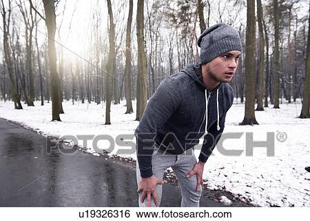 Stock Photograph - Young man exercising in snowy forest. Fotosearch