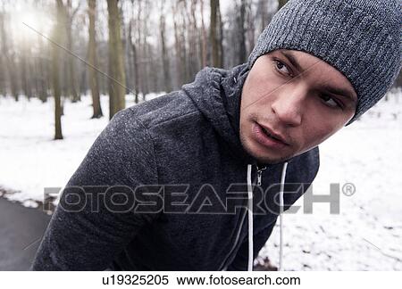Stock Photography - Young man exercising in snowy forest, looking away. Fotosearch
