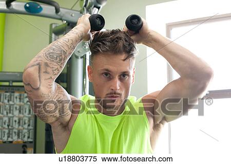 Young man in gym using exercise equipment View Large Photo Image Stock Photography - Young man in gym using exercise equipment. Fotosearch