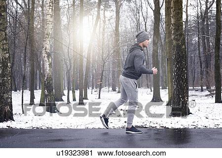 Young man jogging through snowy forest View Large Photo Image Stock Image - Young man jogging through snowy forest. Fotosearch