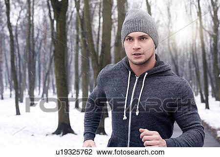 Young man jogging through snowy forest View Large Photo Image Stock Image - Young man jogging through snowy forest. Fotosearch