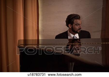 Young man playing piano in bar at night View Large Photo Image Stock Image - Young man playing piano in bar at night. Fotosearch