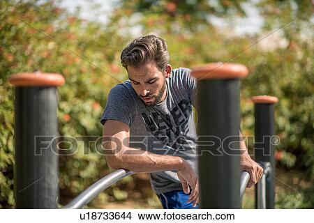 Young man using park exercise equipment, Dubai, United Arab Emirates View Large Photo Image Picture - Young man using park exercise equipment, Dubai, United Arab Emirates. Fotosearch