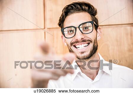 Young man wearing glasses pointing at camera smiling View Large Photo Image Stock Photography - Young man wearing glasses pointing at camera smiling. Fotosearch