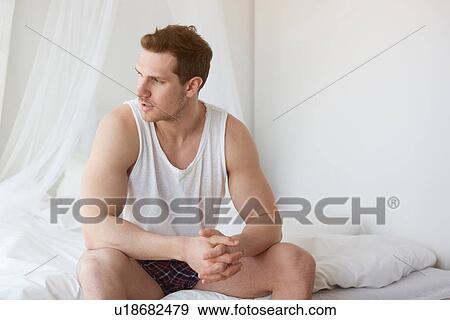 Stock Photo - Young man wearing underwear sitting on bed. Fotosearch
