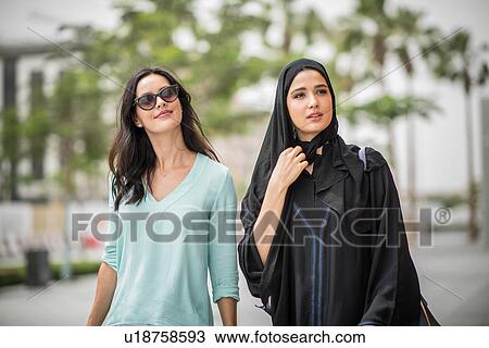 Young middle eastern woman wearing traditional clothing walking along street with female friend, Dubai, United Arab Emirates View Large Photo Image Stock Image - Young middle eastern woman wearing traditional clothing walking along street with female friend, Dubai, United Arab Emirates. Fotosearch