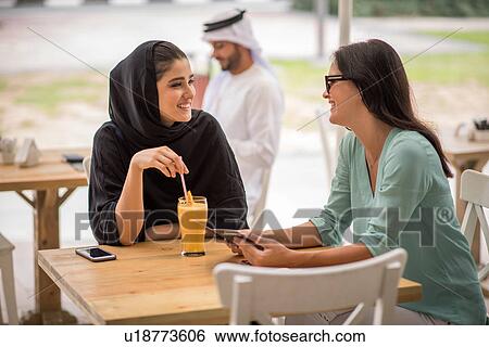 Young middle eastern woman wearing traditional clothing talking with female friend at cafe, Dubai, United Arab Emirates View Large Photo Image Stock Photograph - Young middle eastern woman wearing traditional clothing talking with female friend at cafe, Dubai, United Arab Emirates. Fotosearch
