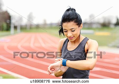 Young woman on running track, checking watch View Large Photo Image Stock Photograph - Young woman on running track, checking watch. Fotosearch