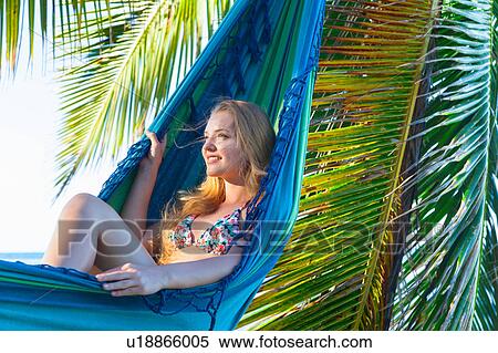 Stock Photography - Young woman reclining in hammock at beach, Dominican Republic, The Caribbean. Fotosearch