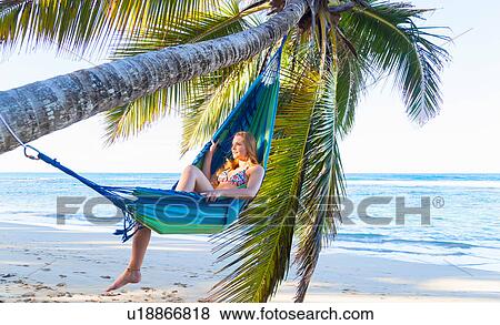 Stock Photo - Young woman reclining in palm tree hammock, Dominican Republic, The Caribbean. Fotosearch