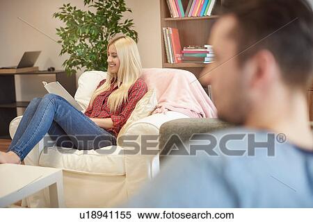 Stock Photography - Young woman sitting at home, reading document, smiling. Fotosearch