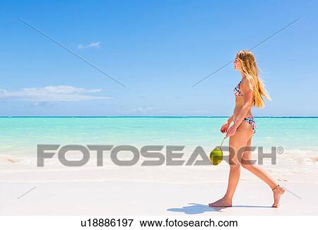Stock Photo - Young woman wearing bikini strolling on beach, Dominican Republic, The Caribbean. Fotosearch