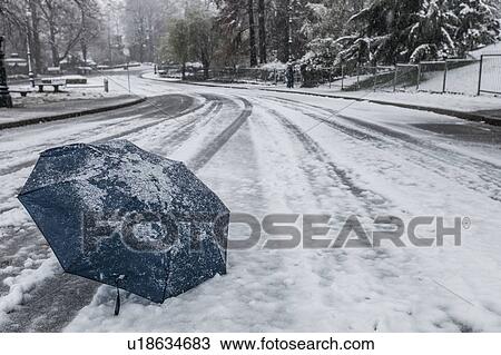 Stock Image - Abandoned umbrella on snow covered road. Fotosearch