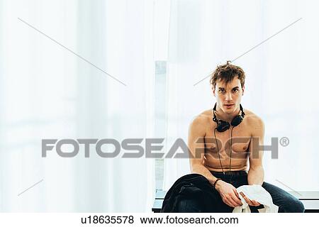 Stock Photo - Bare chested man wearing headphones looking at camera. Fotosearch