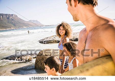 Picture - Bodyboarding couple and children strolling on beach, Cape Town, South Africa. Fotosearch
