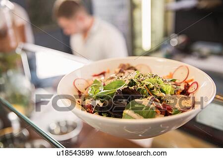 Stock Photo - Bowl of salad on glass counter in restaurant. Fotosearch