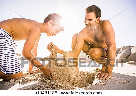 Stock Photograph - Boy and father making sandcastle on beach, Cape Town, South Africa. Fotosearch