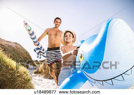 Boy and father running down sand dune carrying shark inflatable, Cape Town, South Africa View Large Photo Image Stock Photo - Boy and father running down sand dune carrying shark inflatable, Cape Town, South Africa. Fotosearch