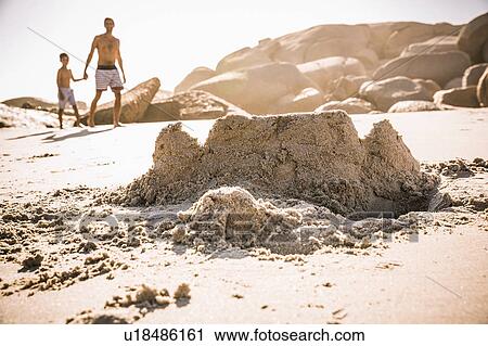 Stock Image - Boy and father strolling on sandcastle beach, Cape Town, South Africa. Fotosearch