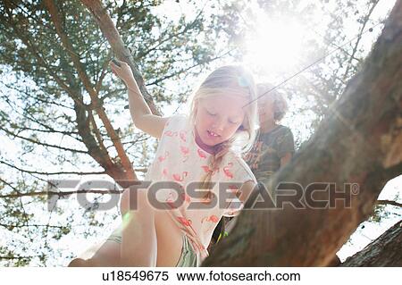 Stock Photography - Boy and girl climbing tree. Fotosearch