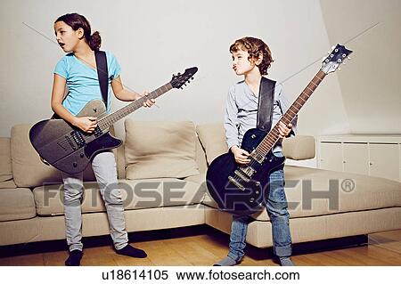 Boy and girl in lounge playing guitars looking away View Large Photo Image Stock Photography - Boy and girl in lounge playing guitars looking away. Fotosearch