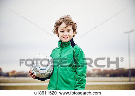 Boy holding football looking at camera smiling View Large Photo Image Stock Image - Boy holding football looking at camera smiling. Fotosearch