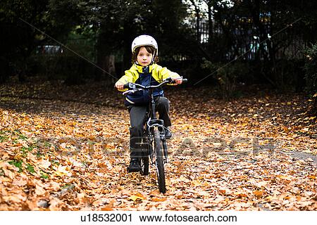 Boy in park wearing cycling helmet riding bicycle View Large Photo Image Stock Image - Boy in park wearing cycling helmet riding bicycle. Fotosearch