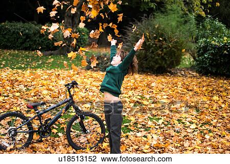 Boy in park with bike throwing autumn leaves View Large Photo Image Stock Image - Boy in park with bike throwing autumn leaves. Fotosearch