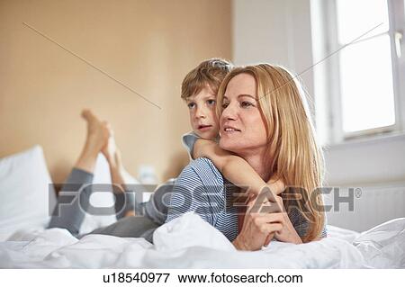 Boy on bed lying on top of mother View Large Photo Image Stock Photo - Boy on bed lying on top of mother. Fotosearch