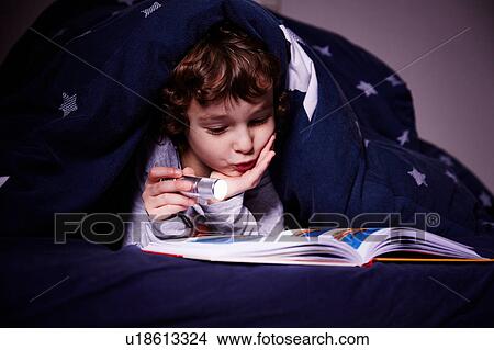Boy underneath duvet reading book by torchlight View Large Photo Image Picture - Boy underneath duvet reading book by torchlight. Fotosearch