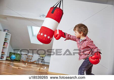 Stock Photography - Boy wearing boxing gloves punching punch bag. Fotosearch