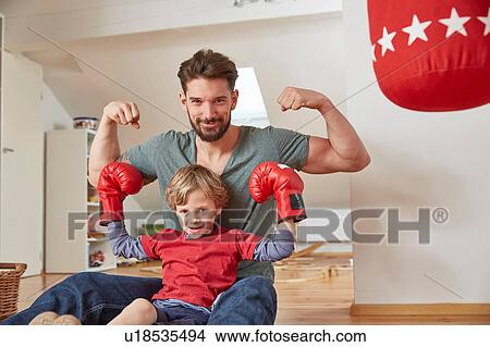 Boy wearing boxing with father, flexing muscles looking at camera View Large Photo Image Picture - Boy wearing boxing with father, flexing muscles looking at camera. Fotosearch