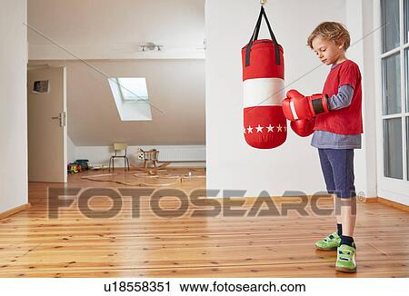 Stock Image - Boy with punch bag putting on boxing gloves. Fotosearch