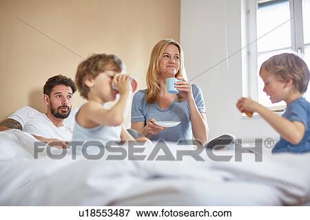 Stock Photo - Boys having breakfast in parents bed. Fotosearch