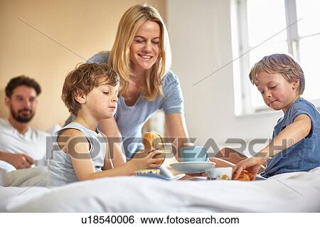Stock Photograph - Boys having breakfast in parents bed. Fotosearch