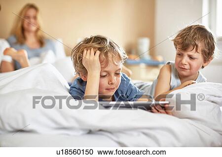 Boys on parents bed using digital tablet View Large Photo Image Stock Image - Boys on parents bed using digital tablet. Fotosearch